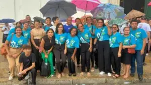 Diversos membros da Comunidade Maíra reunidos na frente da Catedral Metropolitana de Belém vestindo camisas azuis, cada uma segurando um guarda-chuva, criando uma cena vibrante.